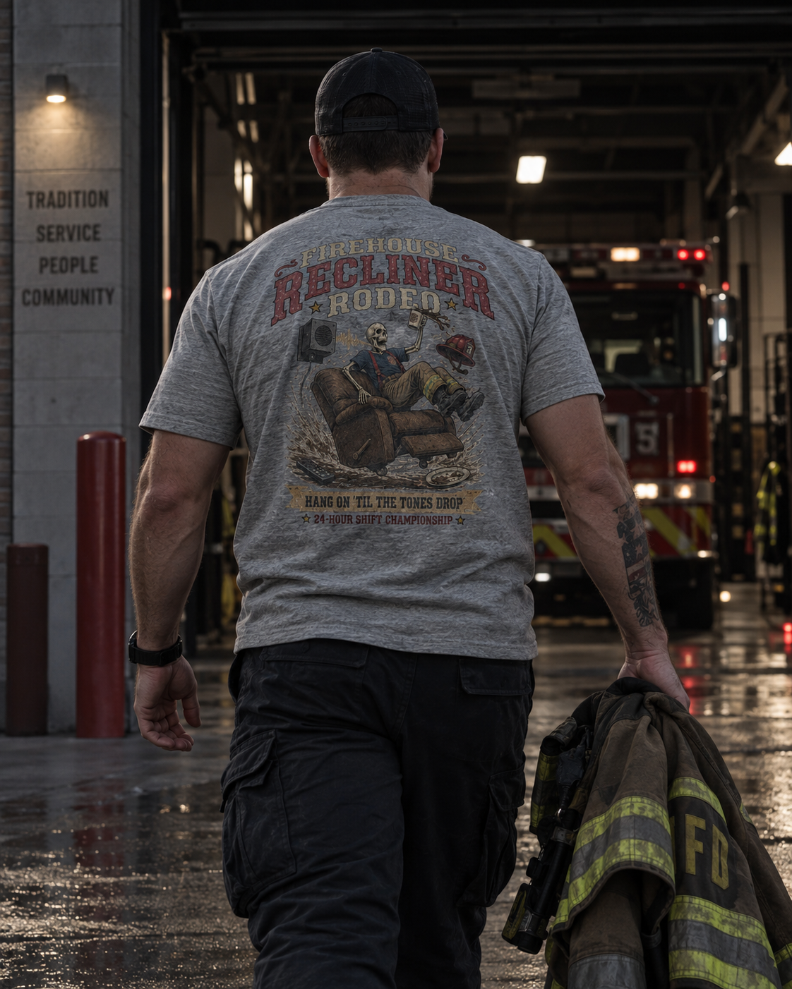 Firefighter walking toward a fire engine while wearing the heather gray Firehouse Recliner Rodeo T-shirt with turnout gear in hand.