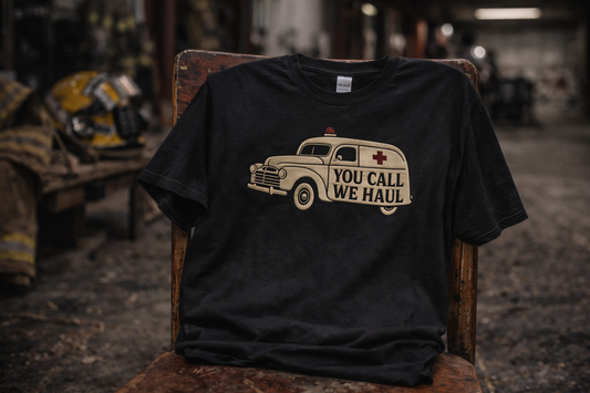 Firehouse Humor You Call We Haul Tee Shirt displayed on a chair in a firehouse setting.